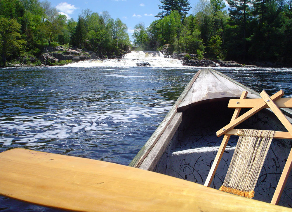 canoe with waterfall in distance and loom in bow